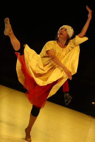 Wearing the yellow smock and fringe headpiece, Koolsil-ja extends her leg above her head